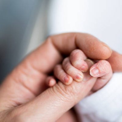 hand of newborn baby who has just been born holding the finger of his father's hand.